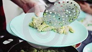 Chef puts ready-made pasta from the pan on a plate in the kitchen. Food ingredient. Cooking in the kitchen. Gourmet