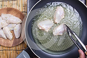 Chef putting chicken wings for fring in pan photo