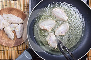 Chef putting chicken wings for fring in pan photo