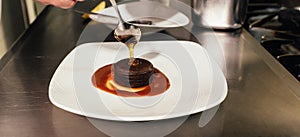 Chef putting the finishing touch on dessert plate while working in a restaurant kitchen.