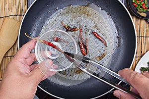 Chef putting fried red dried chlli in the cup