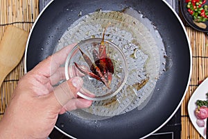 Chef putting fried red dried chlli in the cup