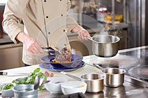 Chef putting lamb shank in plate.