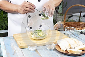 Chef putting minced parsley to bowl for cook garlic bread