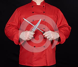 Chef in red uniform sharpens a knife