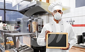 Chef in respirator with chalkboard at kitchen