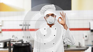 Chef in respirator showing ok sign at kitchen