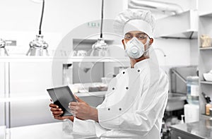 Chef in respirator with tablet pc at kitchen