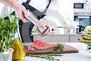 Chef in restaurant kitchen cooking,he is cutting meat or steak