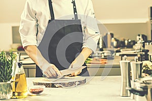 Chef in restaurant kitchen cooking,he is cutting meat or steak