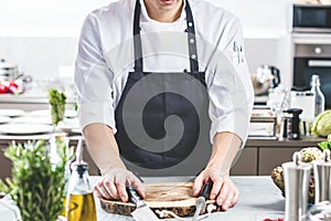 Chef in restaurant kitchen cooking,he is cutting meat or steak