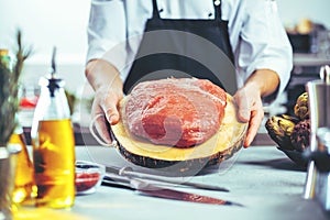 Chef in restaurant kitchen cooking,he is cutting meat or steak