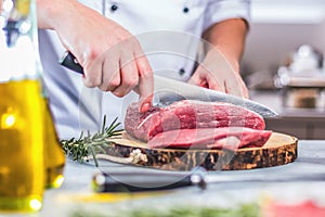 Chef in restaurant kitchen cooking,he is cutting meat or steak