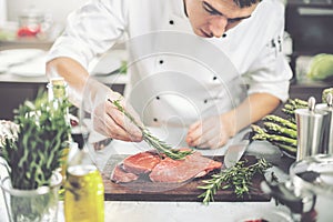 Chef in restaurant kitchen cooking,he is cutting meat or steak