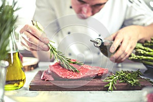 Chef in restaurant kitchen cooking,he is cutting meat or steak