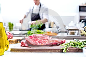 Chef in restaurant kitchen cooking,he is cutting meat or steak