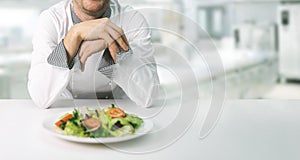 Chef in restaurant kitchen with fresh salad plate