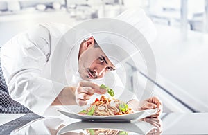 Chef in restaurant kitchen prepares and decorates meal with hands.Cook preparing spaghetti bolognese