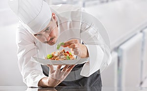 Chef in restaurant kitchen prepares and decorates meal with hands.Cook preparing spaghetti bolognese