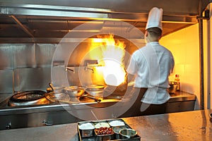 Chef in restaurant kitchen at stove with pan