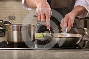 Chef in restaurant kitchen at stove with pan