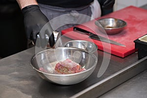 The chef in the restaurant marinates the chicken for the guests.