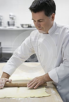 Chef Rolling Dough In Kitchen