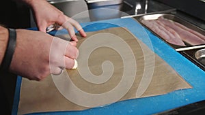 Chef rolling up white cod fish for baking in a Parchment Pape renvelope