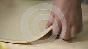 Chef rolls dough layer on wooden board in industrial kitchen