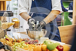 Chef& x27;s gloved hands grating piece of cheese with steel grater in professional kitchen. Cooking pasta, pizza, lasagna