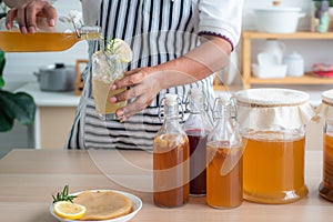 Chef`s hand holds and pouring a bottle and a glass of Homemade fermented kombucha tea