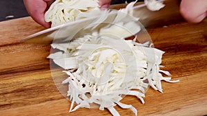Chef's hands cutting onion on the board.
