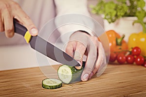 Chef`s hands. Man is ready to prepare fresh salad. Chopping cucumber. photo