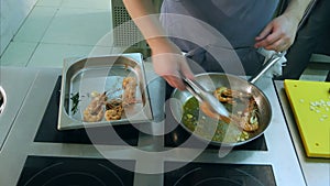 Chef`s hands removing fried shrimps from the pan to a special tray