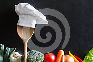 Chef`s hat on spoon and vegetables cooking food background concept