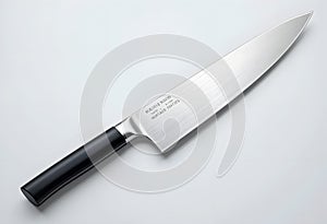 chef's knife with black handle on white surface