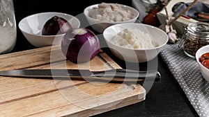 Chef`s knife, red onions, cod fish meat, rice, cherry tomatoes and olives. Ingredients for homemade fish pie. Kitchen still life