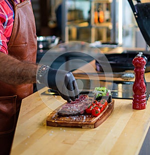 Chef salts steak before grilling in a restaurant