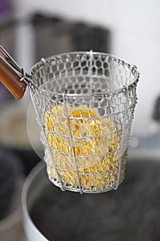 Chef scald raw egg noodles in traditional steel wire mesh