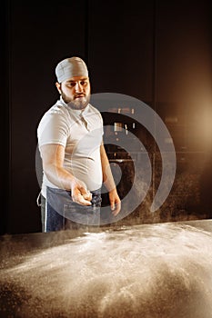 Chef scattering flour on the table for kneading dough