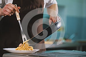 Chef serves spaghetti carbonara on the plate in restaurante