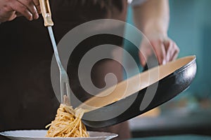 Chef serves spaghetti on the plate in restaurante