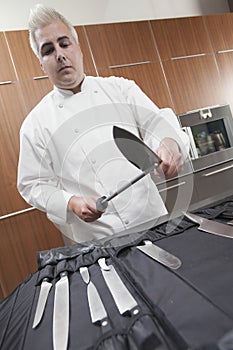 Chef Sharpening Knives In Commercial Kitchen