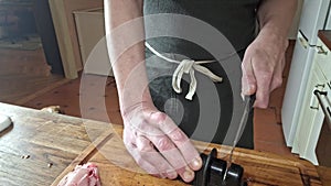 A chef sharpens a knife before preparation. Men hands sharpen a kitchen knife before cutting meat. The concept of