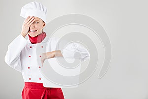 Chef Sign. Woman cook / baker looking over paper sign billboard. Surprised and funny expression woman isolated on white background