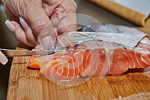 Chef is skinning salmon fillets for cooking