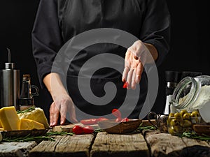 The chef slices tomatoes on a cutting board for Italian focaccia bread. Selected fresh ingredients. Cooking process. Country style