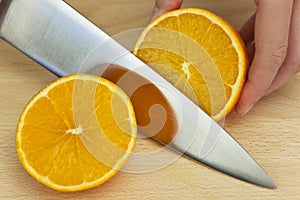 Chef Slicing Fresh Orange With Sharp Kitchen Knife