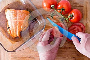 Chef slicing tomatoes to accompany salmon