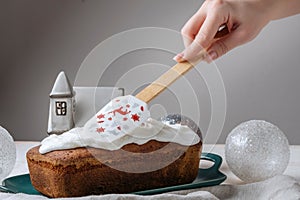 The chef smoothes the icing on the truffle cake, Christmas decorations in the background.